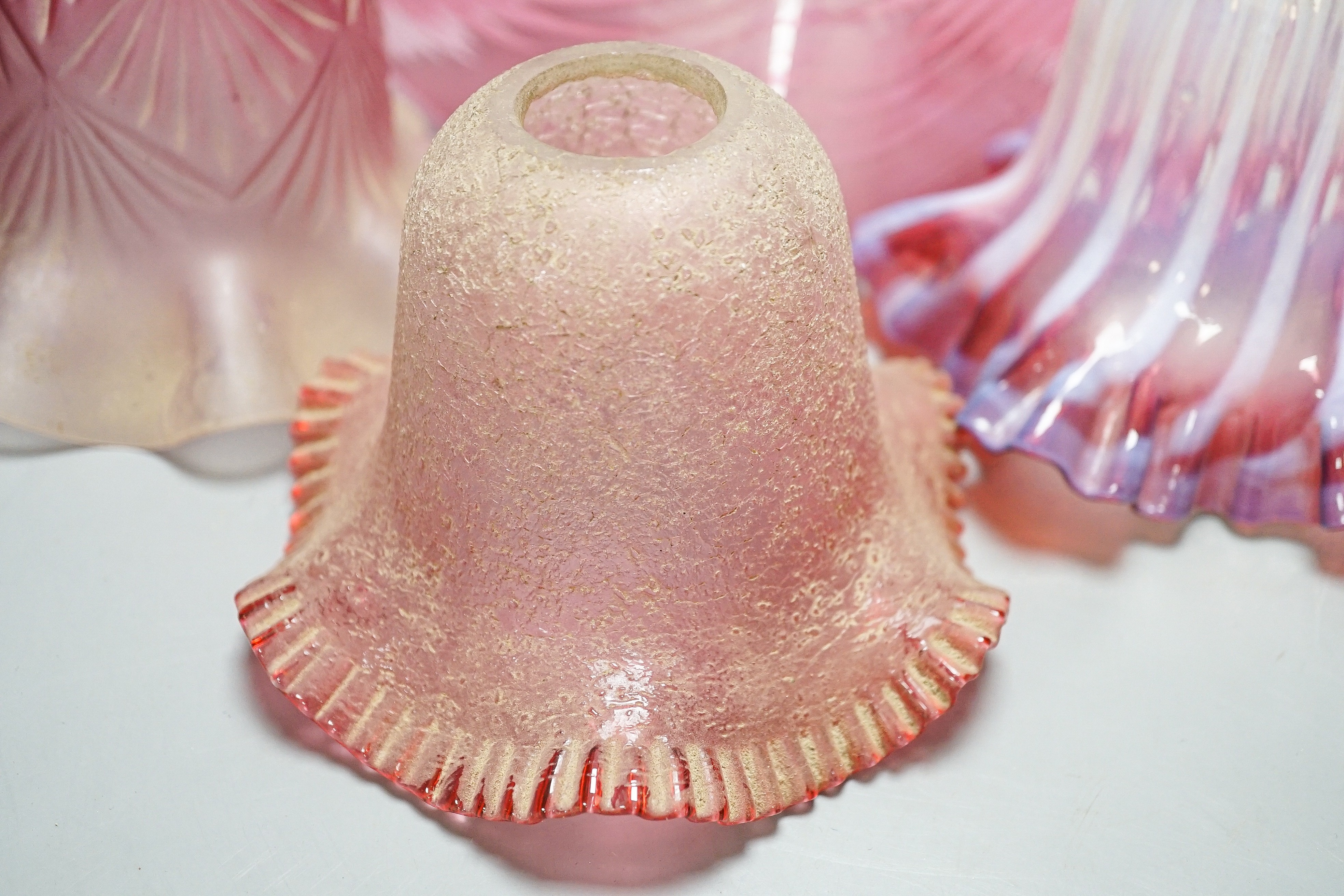Six various cranberry glass lamp shades, two with opalescence, largest 16 cms high.